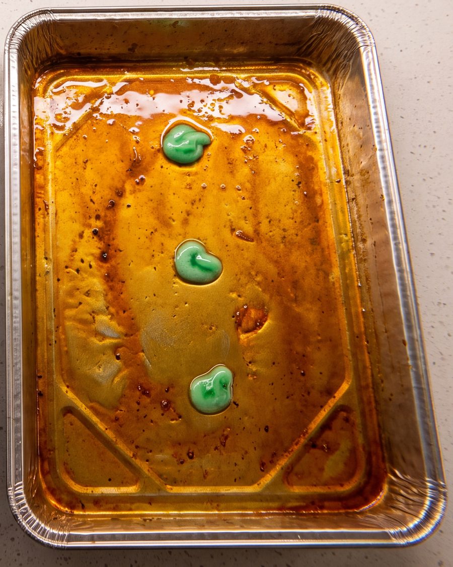 A greasy pan with three small drops of dish soap
